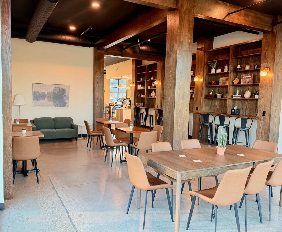The main room at Bayit Brew, set with wood tables, leather chairs, and the built-in bookshelves.