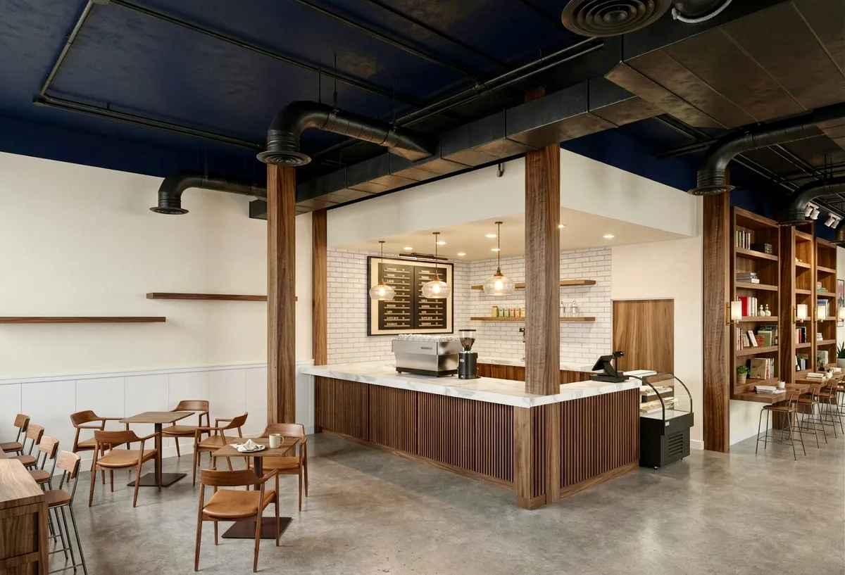 The coffee bar at Bayit Brew, with walnut paneling, marble counter, and pendants overhead.